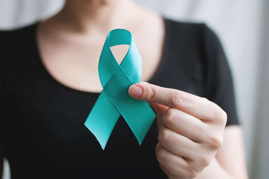 A person holding a blue ribbon shaped like the Cervical Health symbol